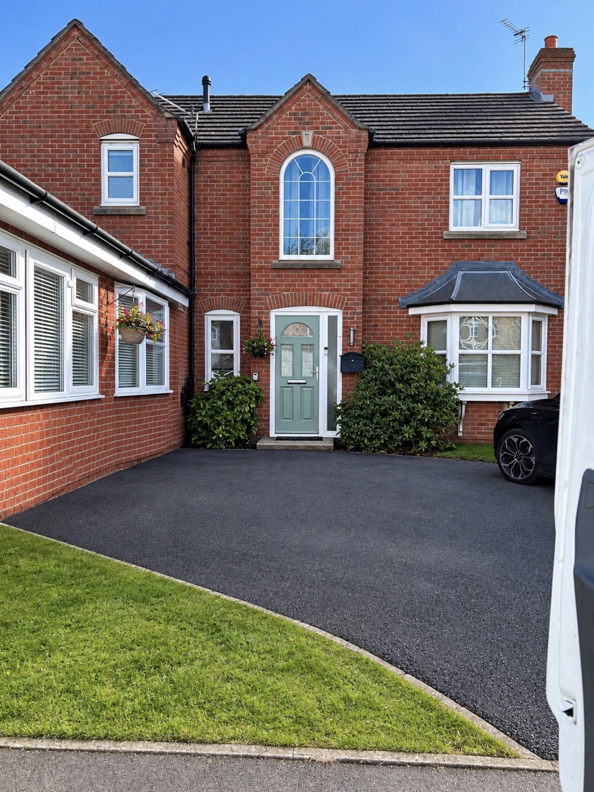 A red brick detached house with new windows, a bay window and a new front door