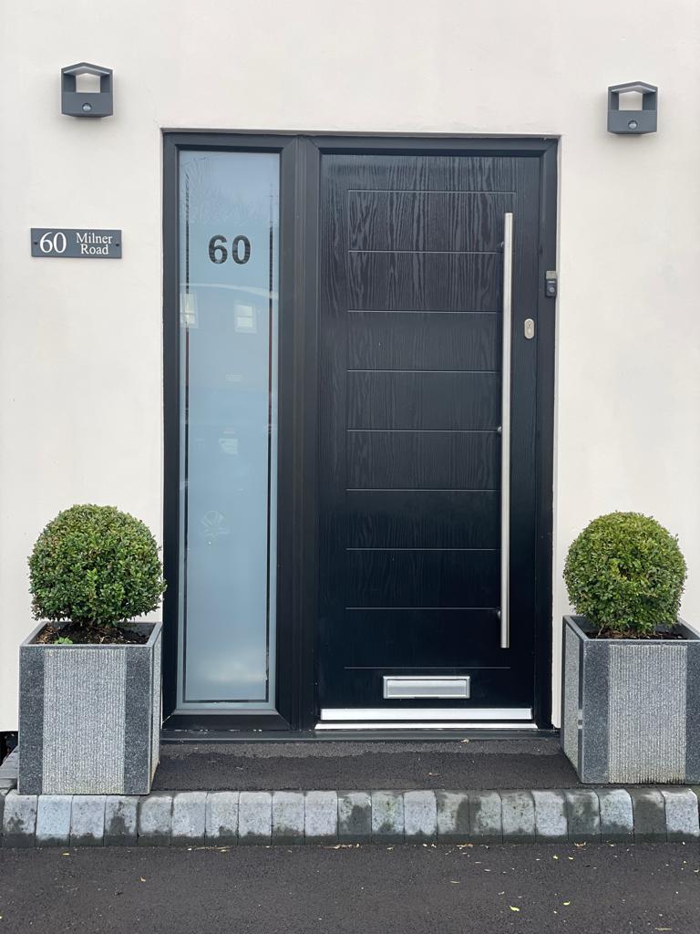 A black composite front door with a tall frosted glass side panel