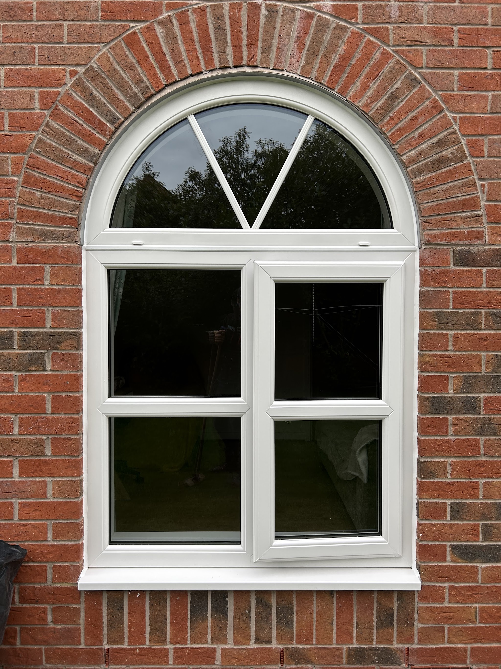 A white arched window set into a brick arch