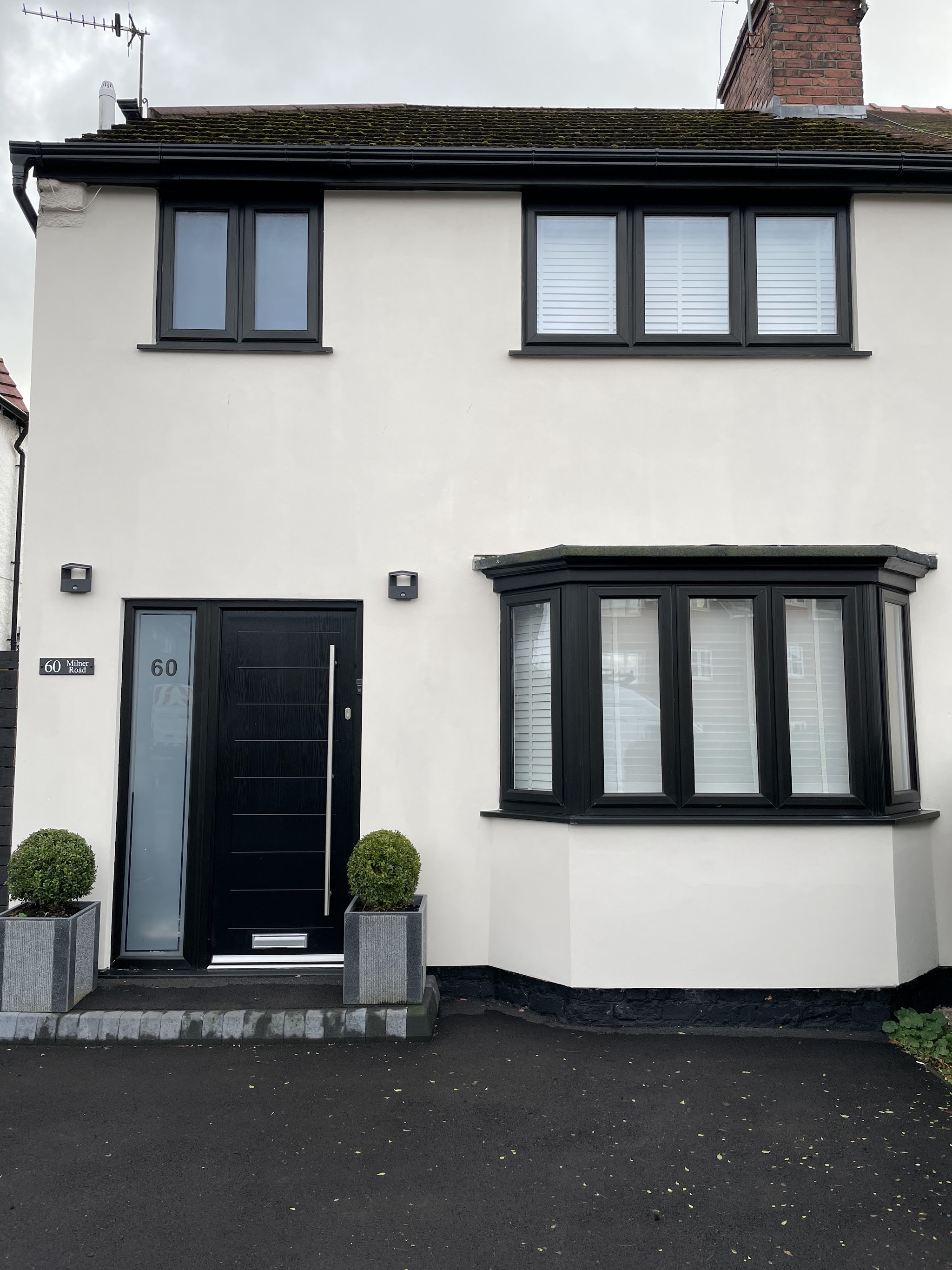 A white rendered house with new black windows, bay window and black front door